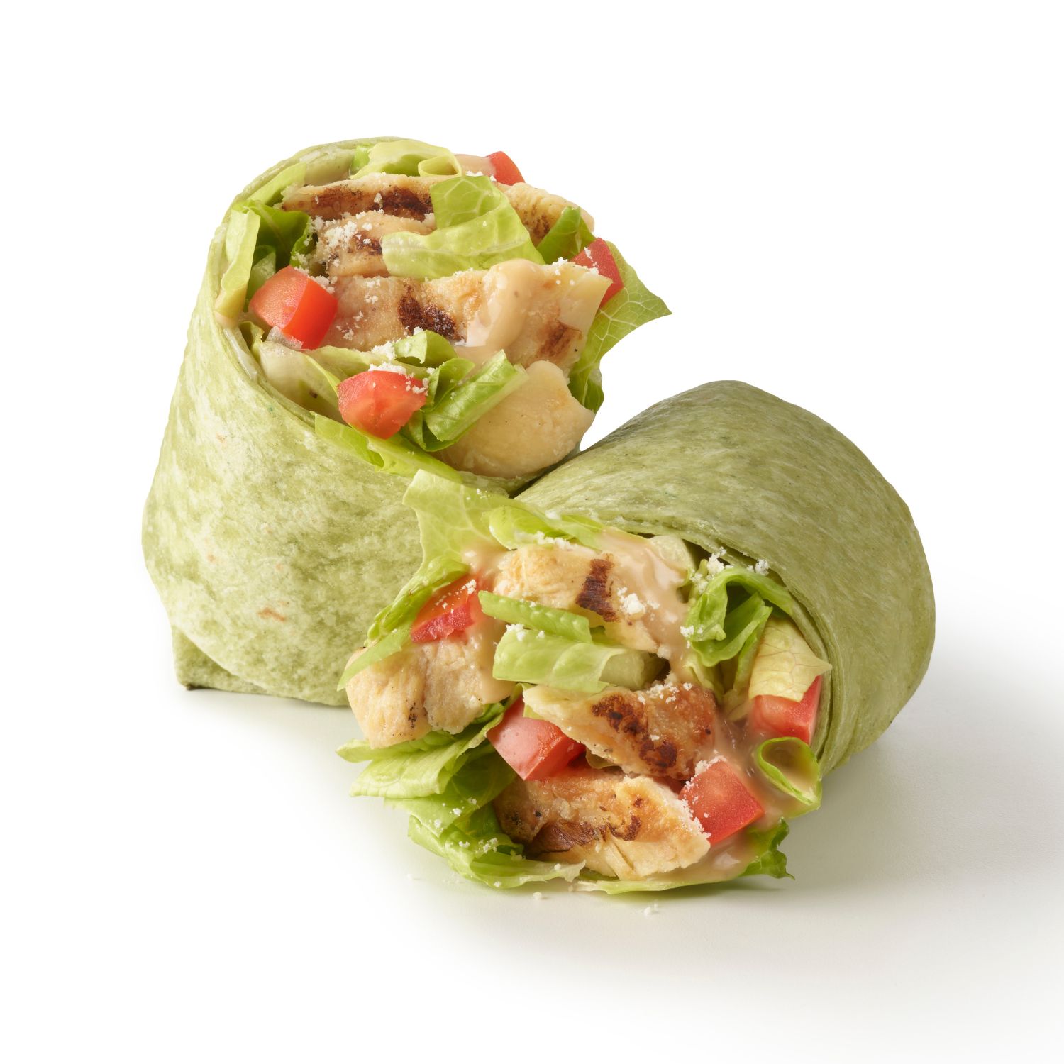 Close-up of a chicken Caesar wrap with grilled chicken, romaine lettuce, tomatoes, parmesan cheese, and Caesar dressing in a spinach tortilla.